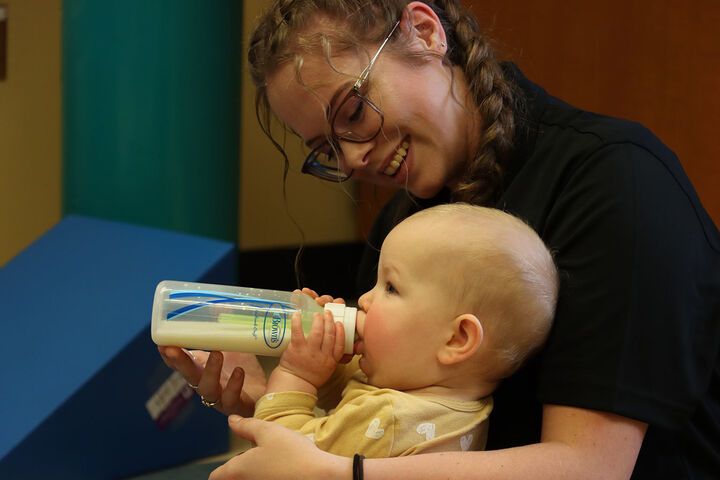 A woman feeds a baby a bottle.